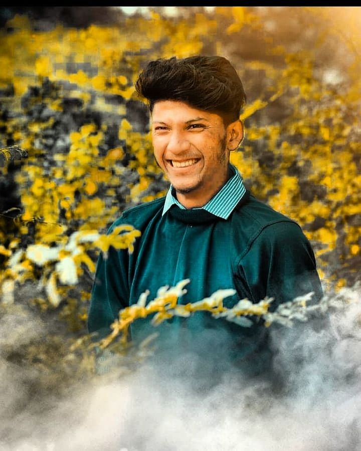 one person, smiling, portrait, waist up, plant, happiness, yellow, looking at camera, adult, young adult, front view, nature, emotion, men, flower, young men, flowering plant, standing, growth, outdoors