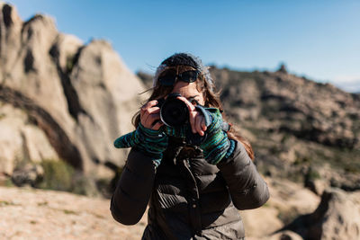 Woman photographing while standing outdoors