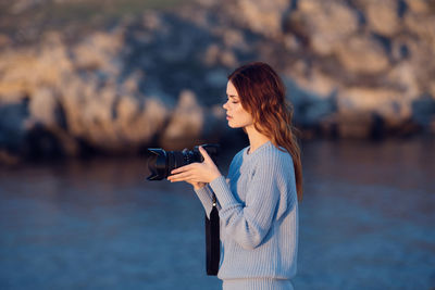 Side view of woman photographing while holding camera