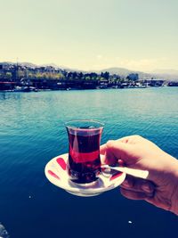 Man drinking glass of water against sky