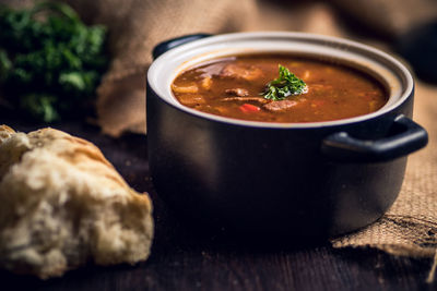 Close-up of soup in bowl by bread on table