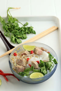 Pho bo, vietnamese fresh rice noodle soup with sliced beef, herbs, and chili.