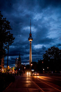 Road passing through city against cloudy sky