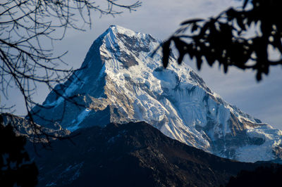 Low angle view of snow covered mountains against blue sky