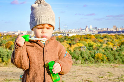 Close-up of boy blowing bubbles on field