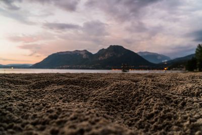 Surface level of sand at beach against cloudy sky during sunset