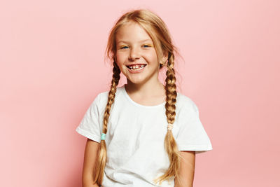 Portrait of young woman against pink background