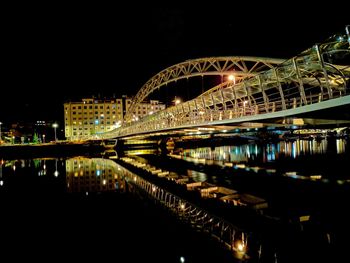 Illuminated bridge over river in city against sky at night