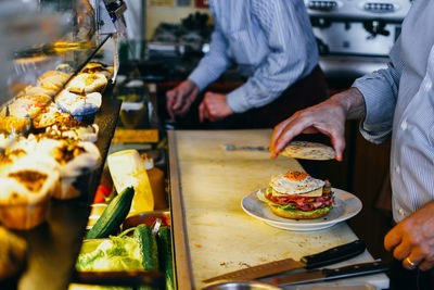 Midsection of people preparing food burger