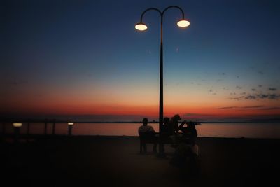 Silhouette people at beach against sky during sunset