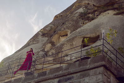 Woman in a long purple dress stands at the entrance to the rock in cappadocia