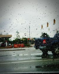 Road seen through wet glass window in rainy season