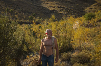 Full length of shirtless man standing on land