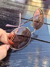 High angle view of hand holding sunglasses on table
