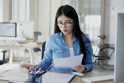 Young woman using mobile phone while sitting on table