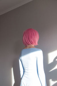 Rear view of woman standing against wall