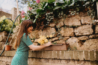 Side view of smiling woman looking flowers