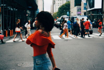 Rear view of people walking on road in city