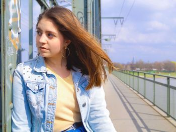 Beautiful young woman looking away against sky