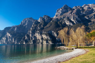 Scenic view of lake and mountains against clear blue sky