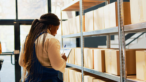 Side view of young woman standing against building