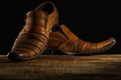 Close-up of shoes on table against black background