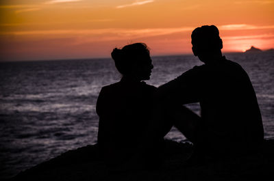 Silhouette man looking at sea against sky during sunset