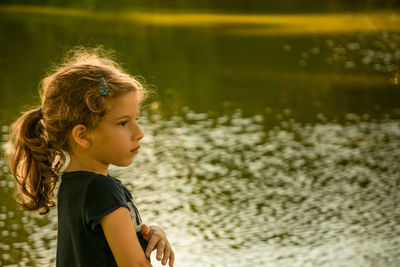 Close-up side view of girl standing by lake