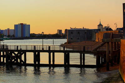 River by buildings against sky during sunset