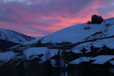 Houses on snowcapped mountain against sky during sunset