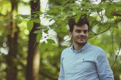 Portrait of young man standing against trees