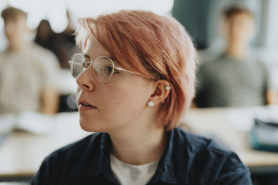 Non-binary person with pink hair wearing eyeglasses at high school