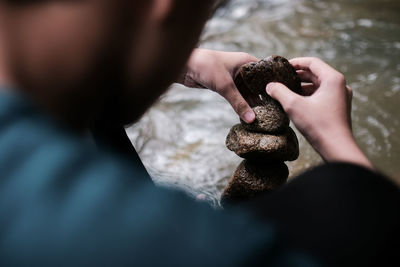 Close up of a boy stacking stones by the stream