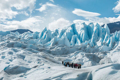 Group of people on snowcapped landscape against sky