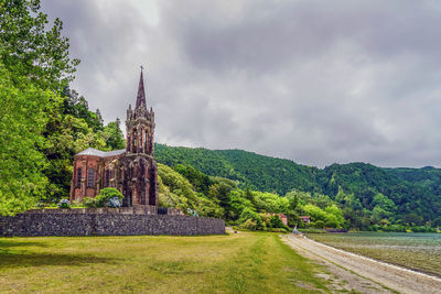 Chapel by lake against sky