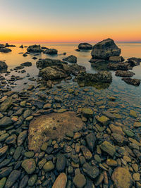 Rocks on beach against sky during sunset