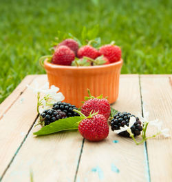 Strawberries and blackberries on wooden table at lawn