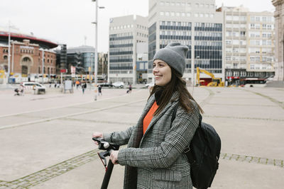 Happy woman with electric push scooter in city