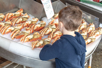 Full length of boy eating food at market stall