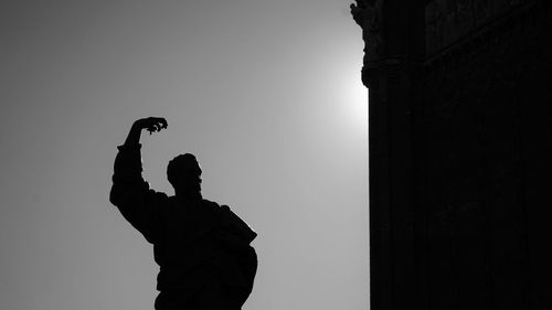 Low angle view of silhouette statue against clear sky