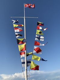 Low angle view of flags against blue sky