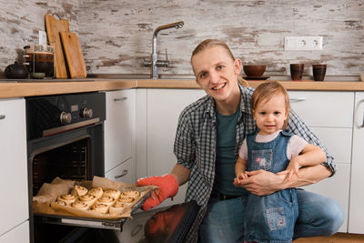 Father and kid waiting for freshly baked buns bread, cinnabons or pastry near the oven happy time