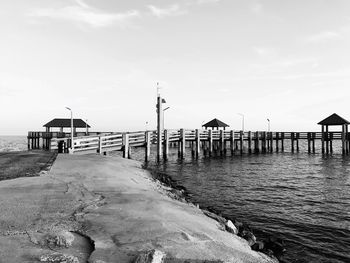 Pier on beach by sea against sky