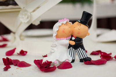 Close-up of bridegroom figures on table with rose petals