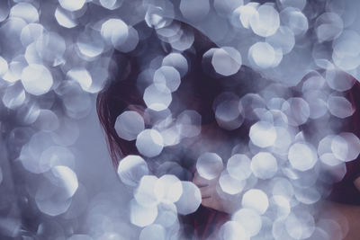 Defocused image of illuminated lights against woman