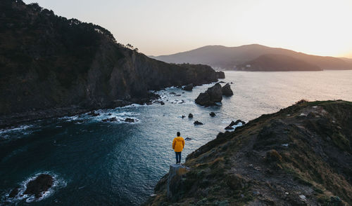 People on rock by sea against sky