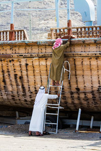 Rear view of men climbing on boat