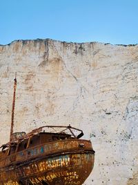 Abandoned boat moored against clear blue sky