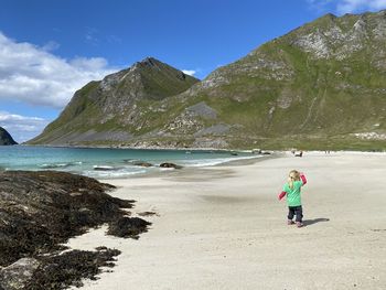 Rear view of girl on beach against sky