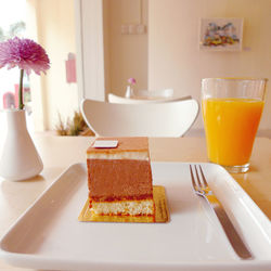 Close-up of cake slice and orange juice on restaurant table